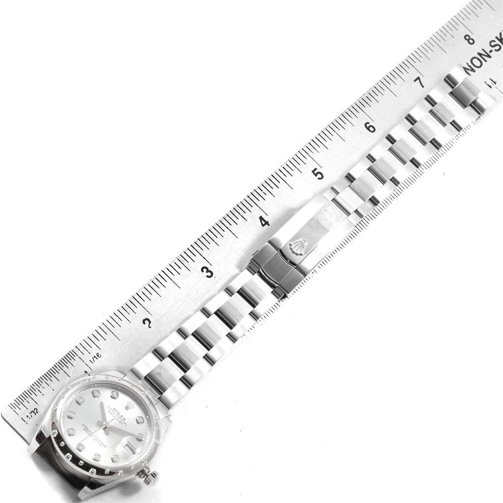 The image shows a top-down view of a Rolex Mid-Size 178344 Women's Stainless Steel Silver Dial 178344 Women's Stainless Steel Silver Dial model watch and its bracelet alongside a ruler.
