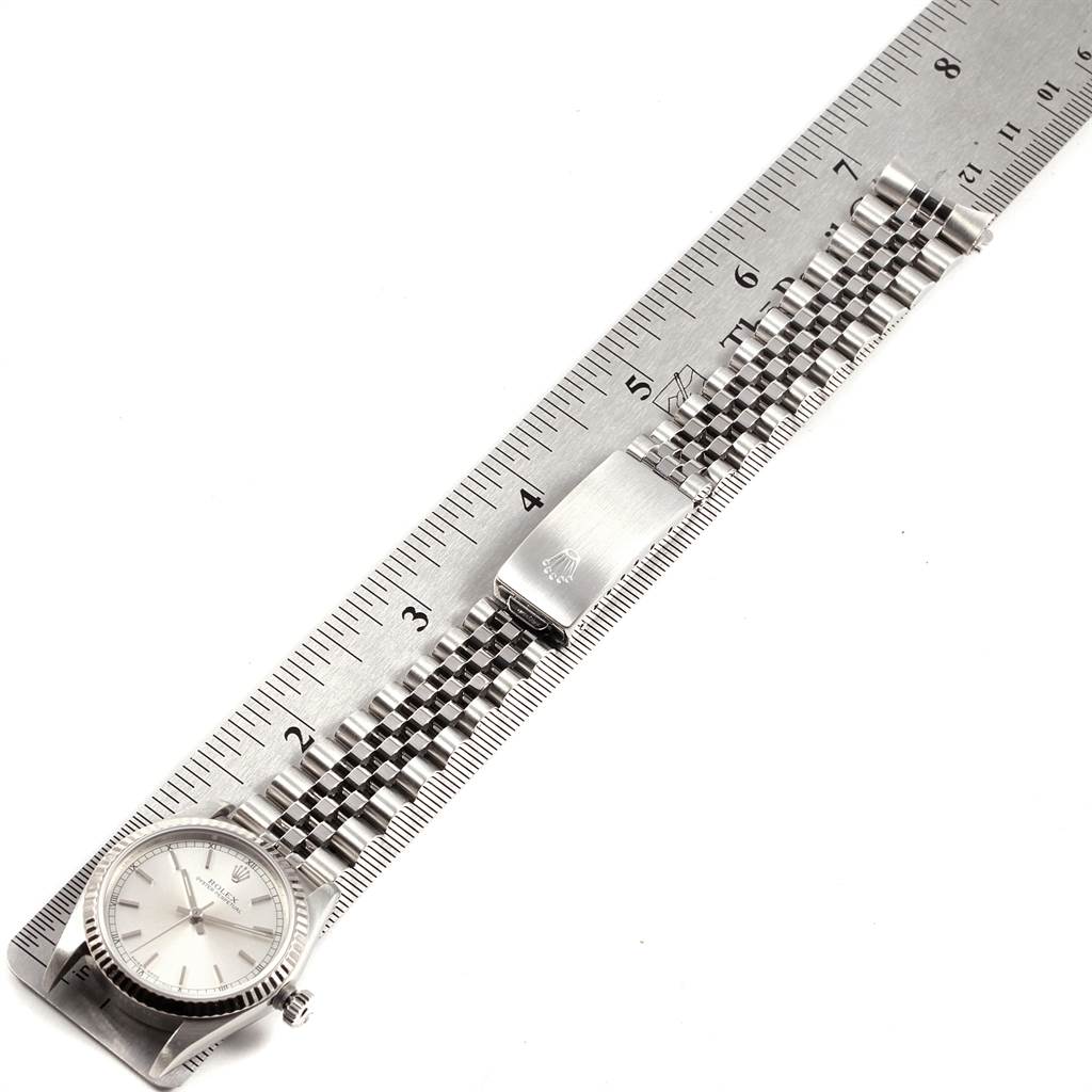 The image shows a Rolex Mid-Size 77014 Women's Stainless Steel Silver Dial 77014 Women's Stainless Steel Silver Dial watch laid flat next to a ruler, displaying the watch face, bracelet, and clasp.