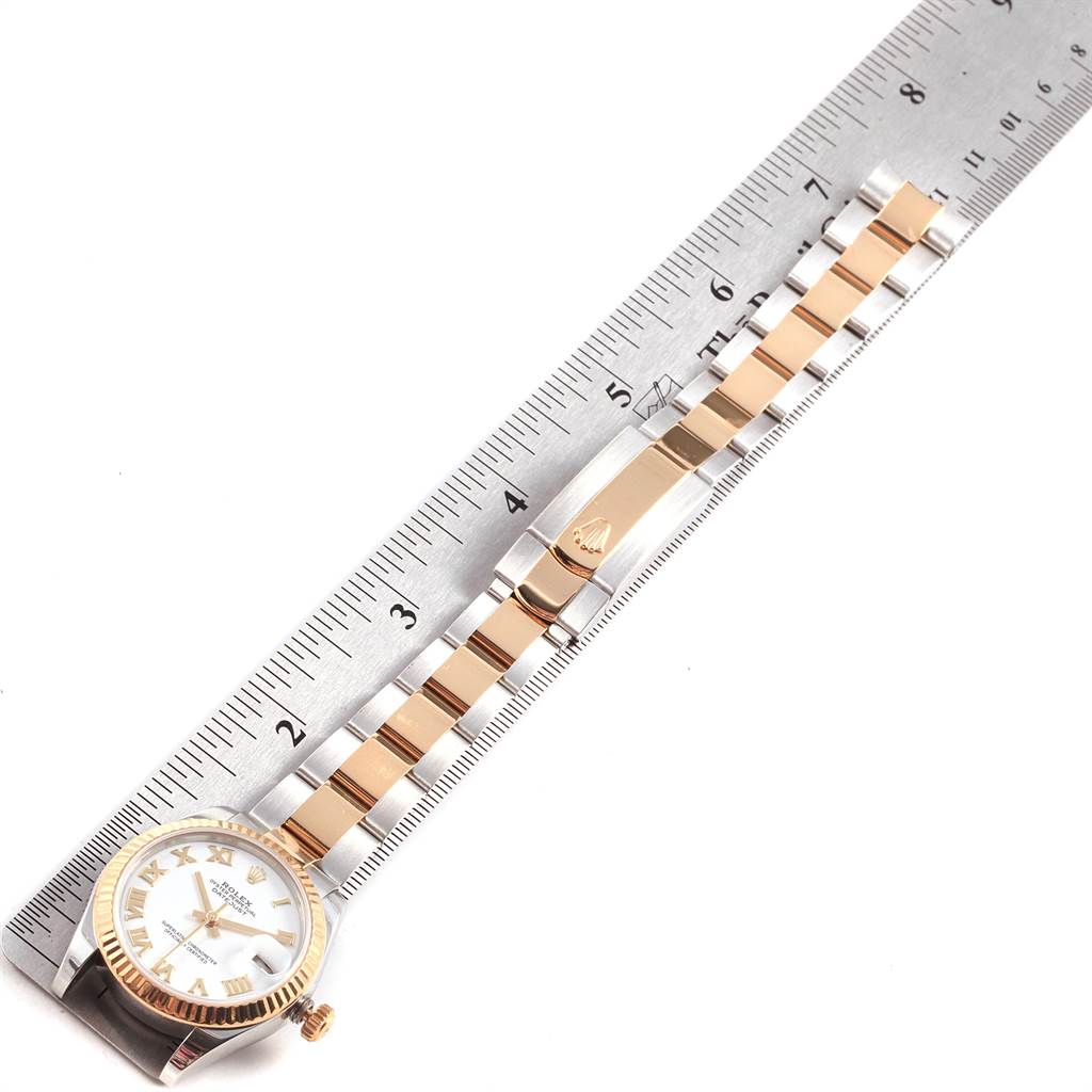 The image shows a Rolex Mid-Size 178273 Women's Steel and Gold (two tone) White Dial 178273 Women's Steel and Gold (two tone) White Dial watch laid flat on a ruler, displaying its face, band, and clasp.