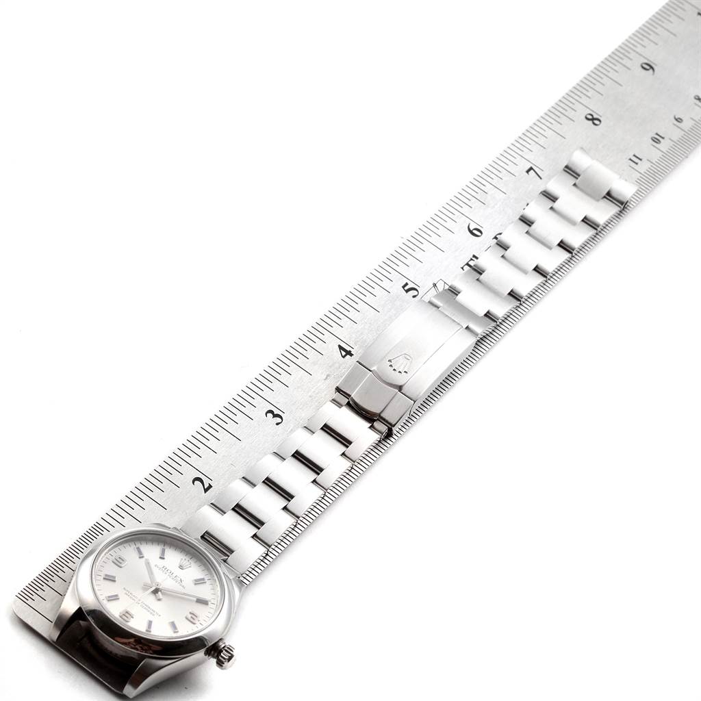 This image shows a Rolex Mid-Size 177200 Women's Stainless Steel Silver Dial 177200 Women's Stainless Steel Silver Dial watch and its metal bracelet laid flat next to a ruler.