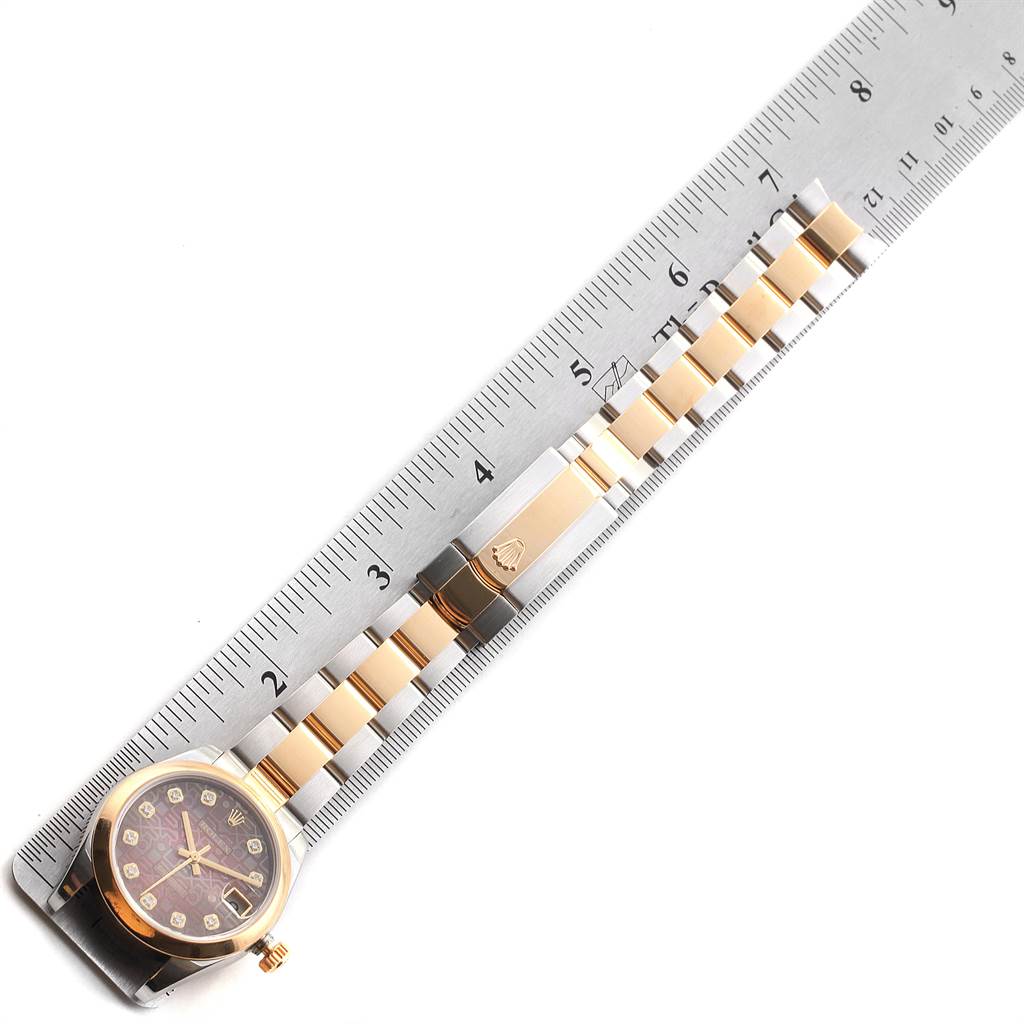 The Rolex Mid-Size 178243 Women
s Stainless Steel Mother of Pearl Dial 178243 Women
s Stainless Steel Mother of Pearl Dial watch is shown from a top-down angle, with a ruler alongside for scale, highlighting its face and bracelet.