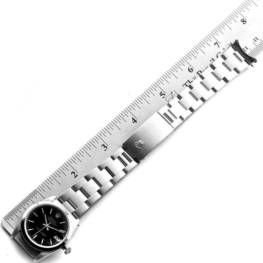 The image shows a side view of a Rolex Mid-Size 68240 Women's Stainless Steel Black Dial 68240 Women's Stainless Steel Black Dial model watch with a ruler, displaying its bracelet and clasp.