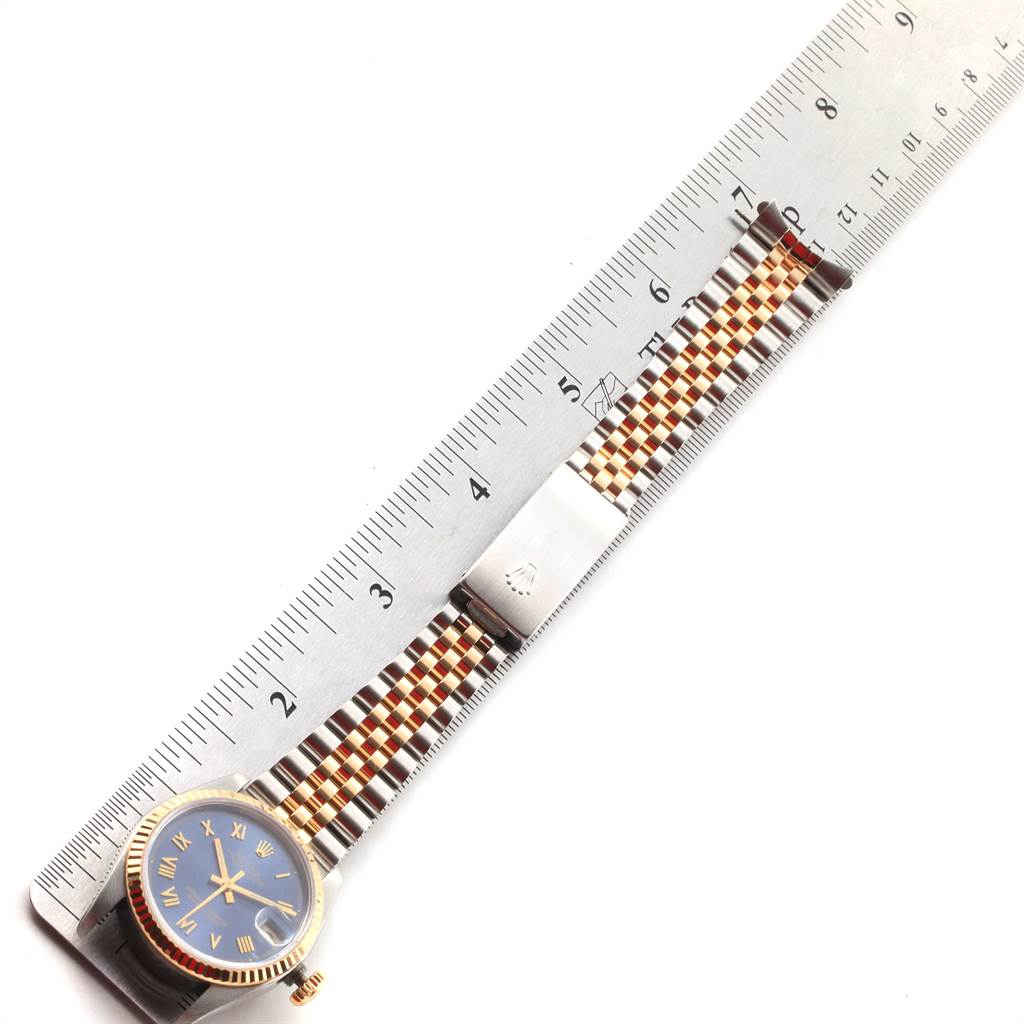 This image shows a Mid-Size Rolex watch laid flat with its band extended next to a ruler for measurement.