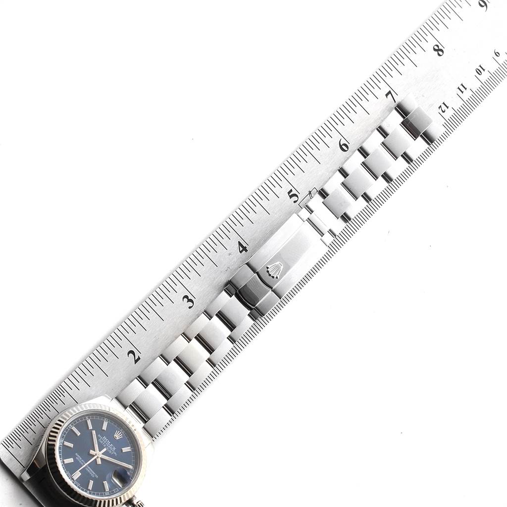 The image shows the watch face and a portion of the band of a Mid-Size Rolex model, alongside a ruler for size reference.