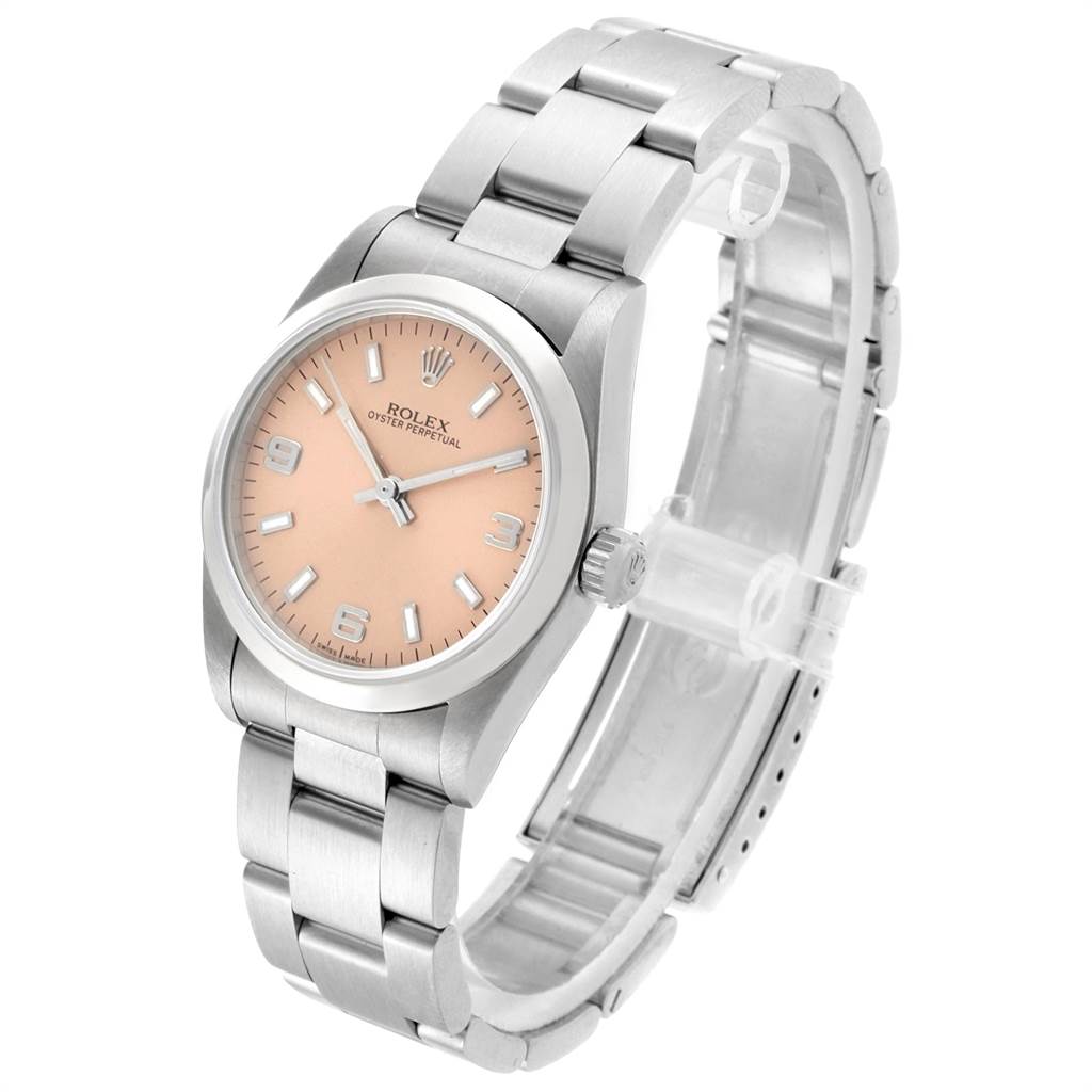 The image shows a Rolex Oyster Perpetual Mid-Size watch, featuring a side angle and highlighting its peach dial and metal bracelet.