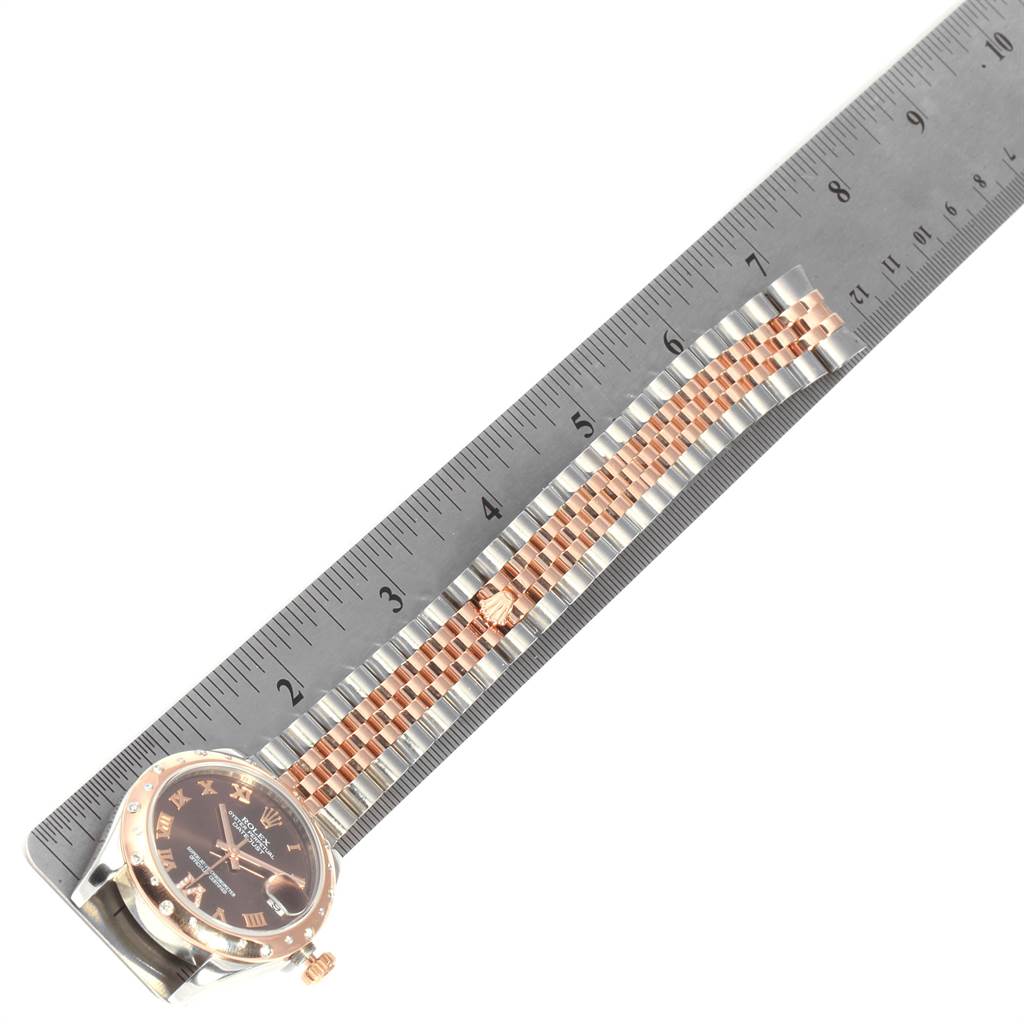 The image shows a Rolex Mid-Size 178341 Women's Steel and Gold (two tone) Brown Dial 178341 Women's Steel and Gold (two tone) Brown Dial watch placed beside a ruler, highlighting its case, bracelet, and clasp.