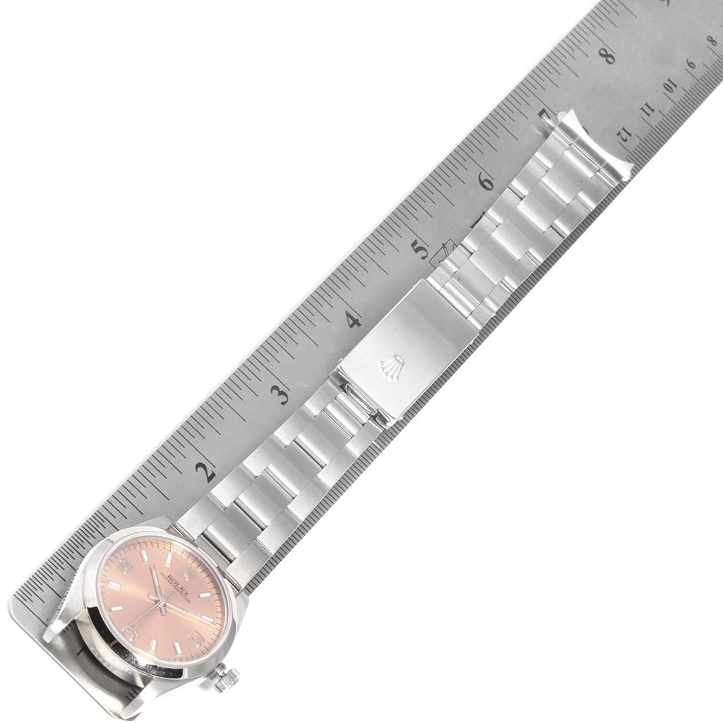 The Rolex Mid-Size 77080 Women's Stainless Steel Pink Dial 77080 Women's Stainless Steel Pink Dial watch is shown in a top-down angle, displaying the dial, bracelet, and clasp, alongside a ruler for size reference.