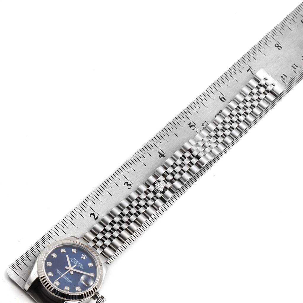 The watch is a Mid-Size Rolex, showing a close-up of the face and part of the bracelet next to a ruler for scale.