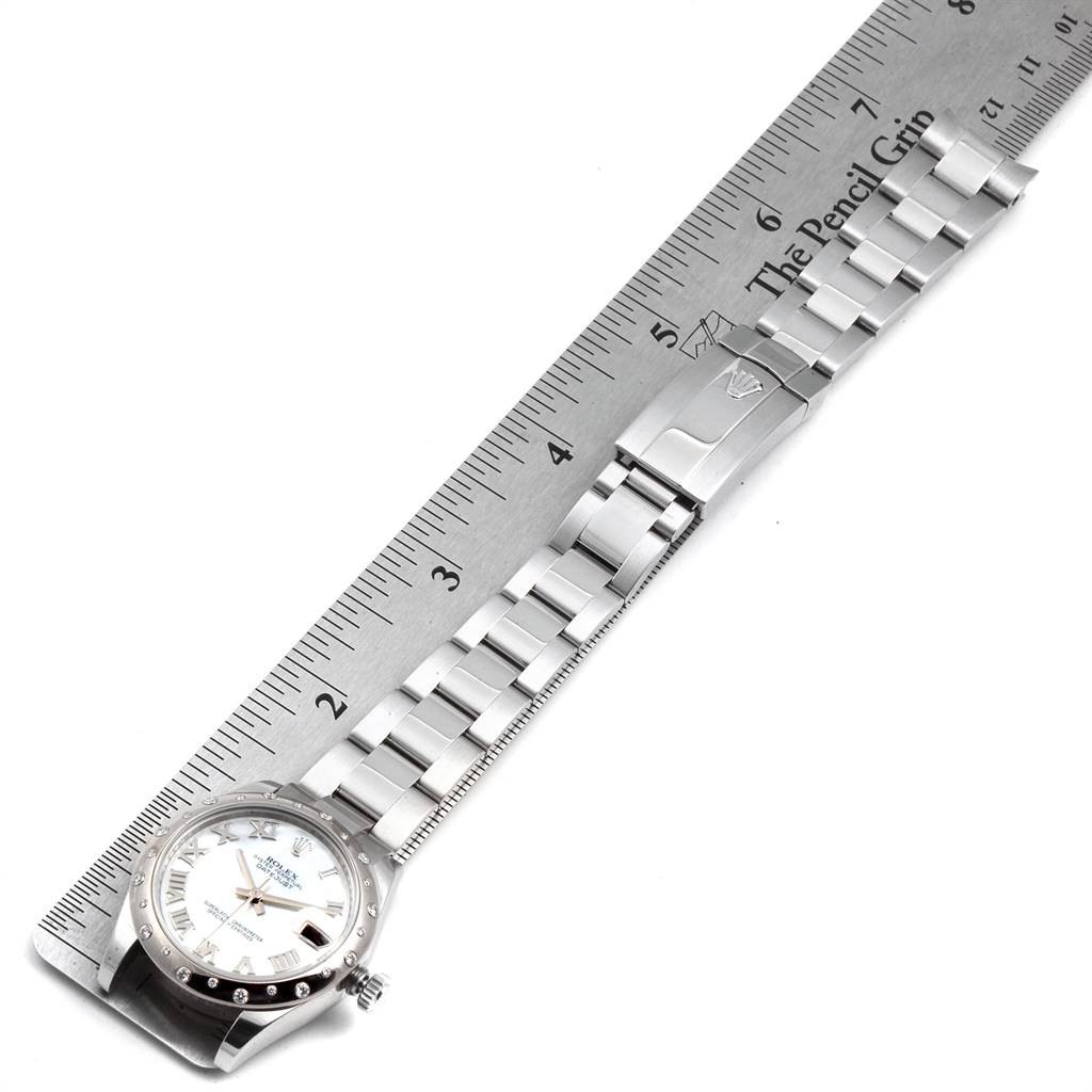 The image shows a Mid-Size Rolex watch laid flat next to a ruler, displaying its bracelet and face.