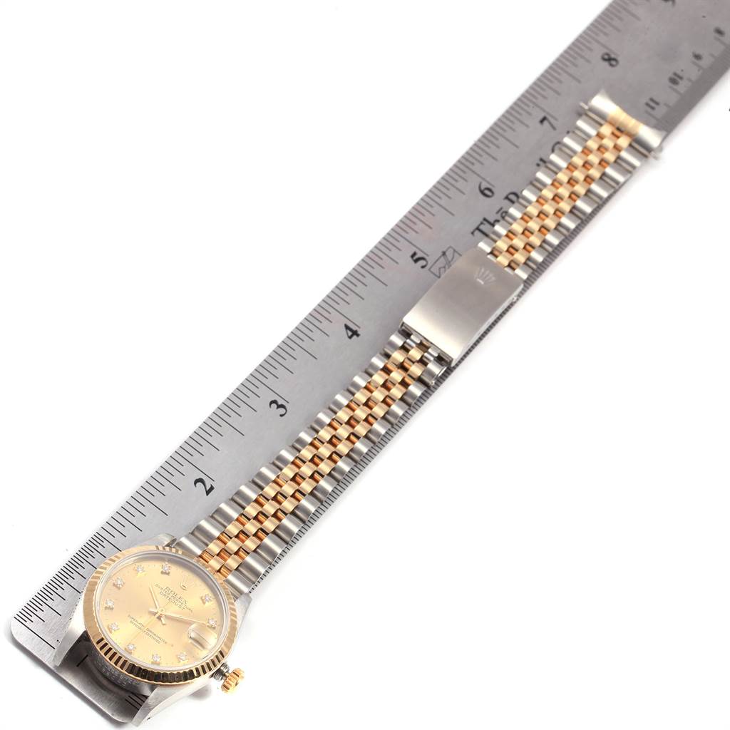 This image shows the Rolex Mid-Size 68273 Women's Steel and Gold (two tone) Champagne Dial 68273 Women's Steel and Gold (two tone) Champagne Dial watch lying flat along a ruler, displaying the face, crown, and full bracelet.