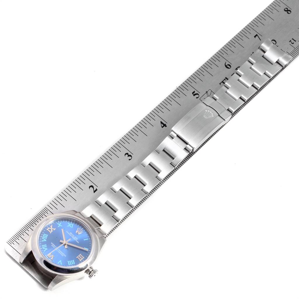 The Rolex Mid-Size 177200 Women's Stainless Steel Blue Dial 177200 Women's Stainless Steel Blue Dial model watch is shown in a top-down view, featuring a blue dial, stainless steel case, and an extended portion of the metal bracelet against a ruler.