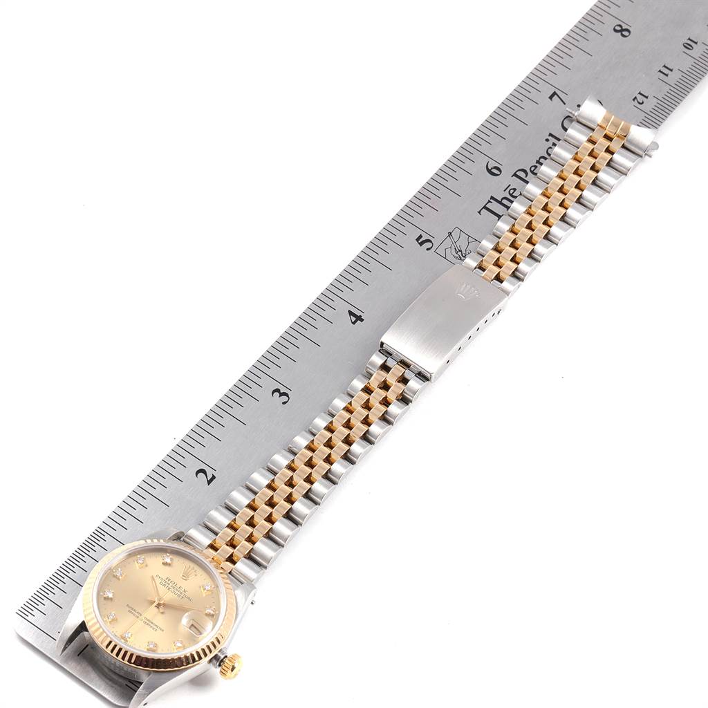 The image shows a Mid-Size Rolex watch laid flat with its dial, bracelet, and clasp alongside a ruler for scale.