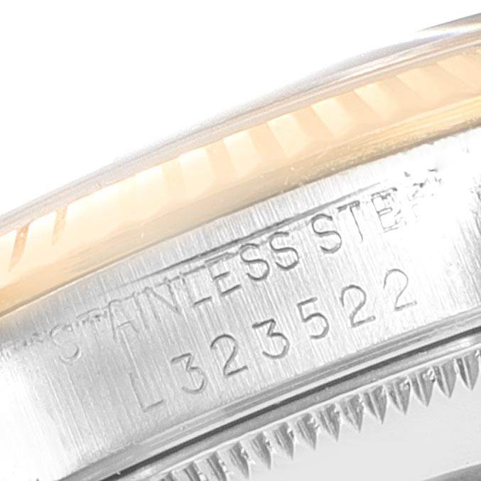 The close-up image of the Rolex Mid-Size 68273 Women's Steel and Gold (two tone) Champagne Dial 68273 Women's Steel and Gold (two tone) Champagne Dial watch shows part of the case with engraving, including the serial number and "STAINLESS STEEL."