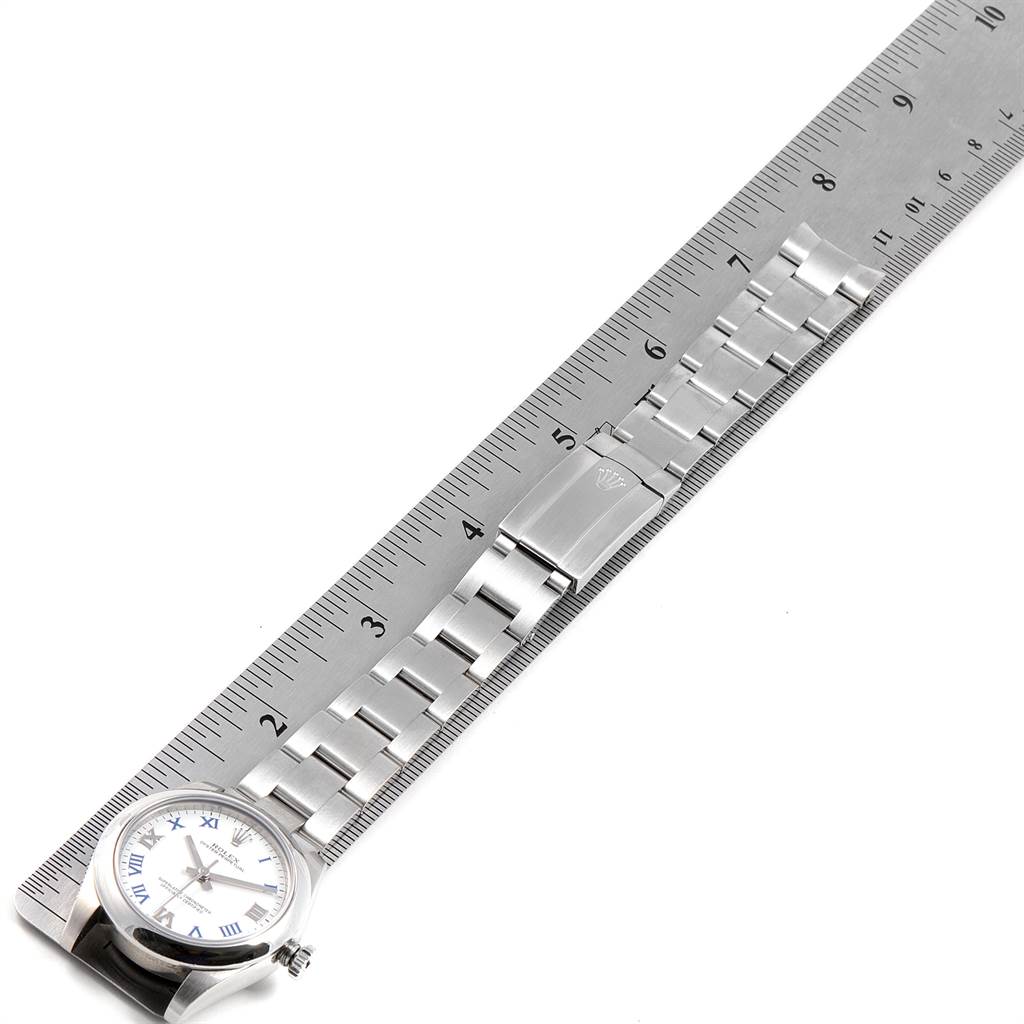 The image shows a Rolex Mid-Size 177200 Women
s Stainless Steel White Dial 177200 Women
s Stainless Steel White Dial model watch lying flat next to a ruler, displaying the watch face, band, and clasp.