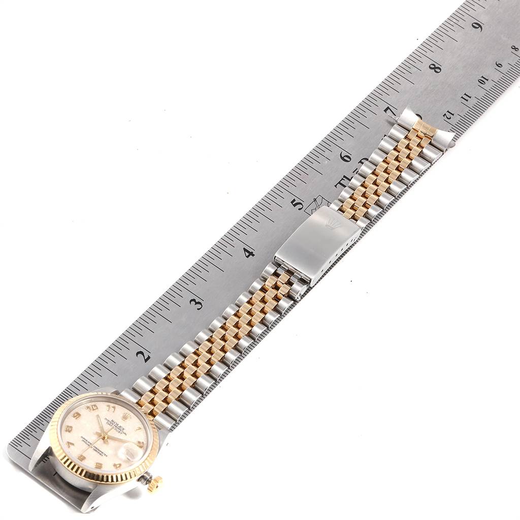The image shows a Mid-Size Rolex watch laid flat next to a ruler, highlighting the dial, bracelet, and clasp.