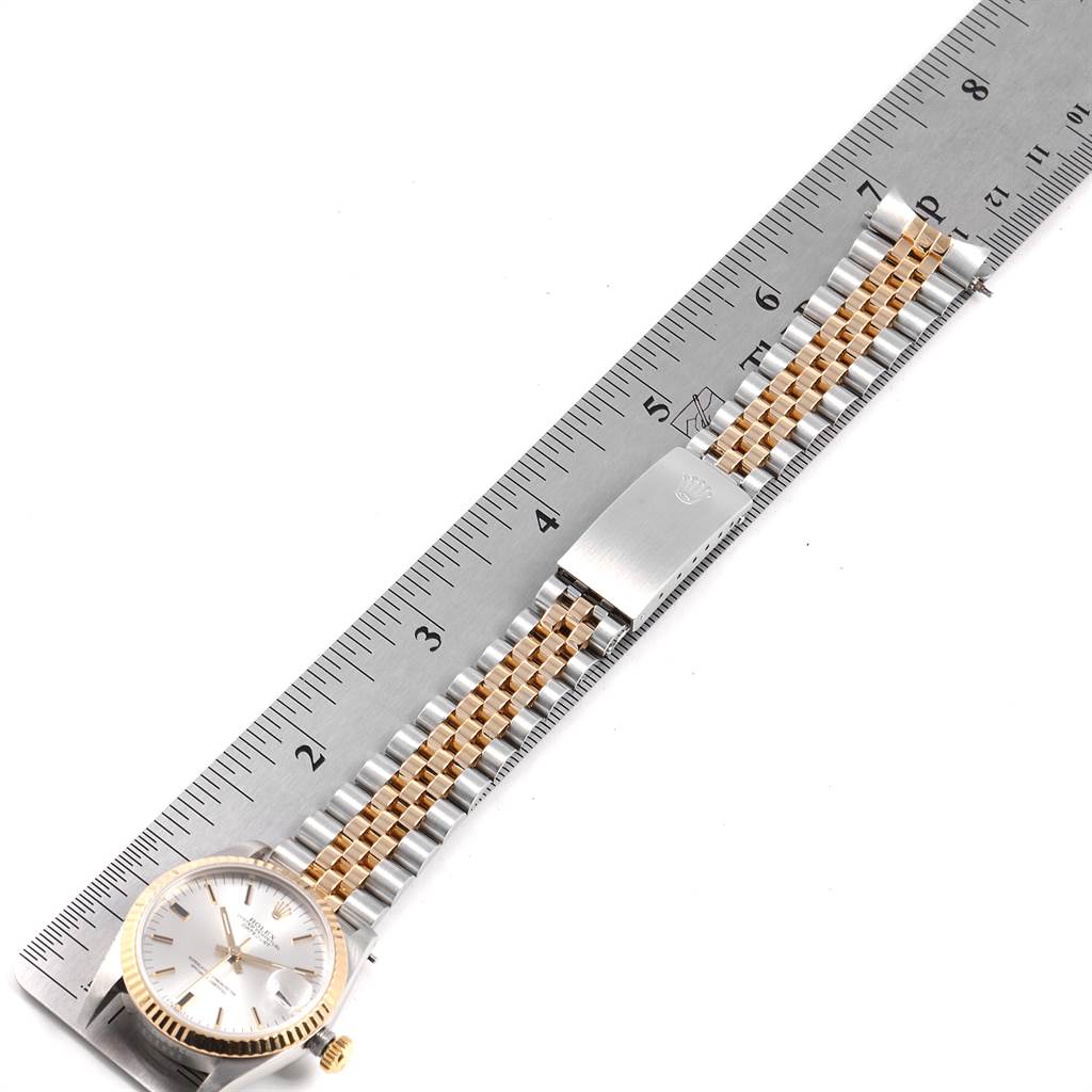 The image shows a flat-lay view of a Mid-Size Rolex watch, displaying the face, bracelet, and clasp aligned with a ruler for scale.