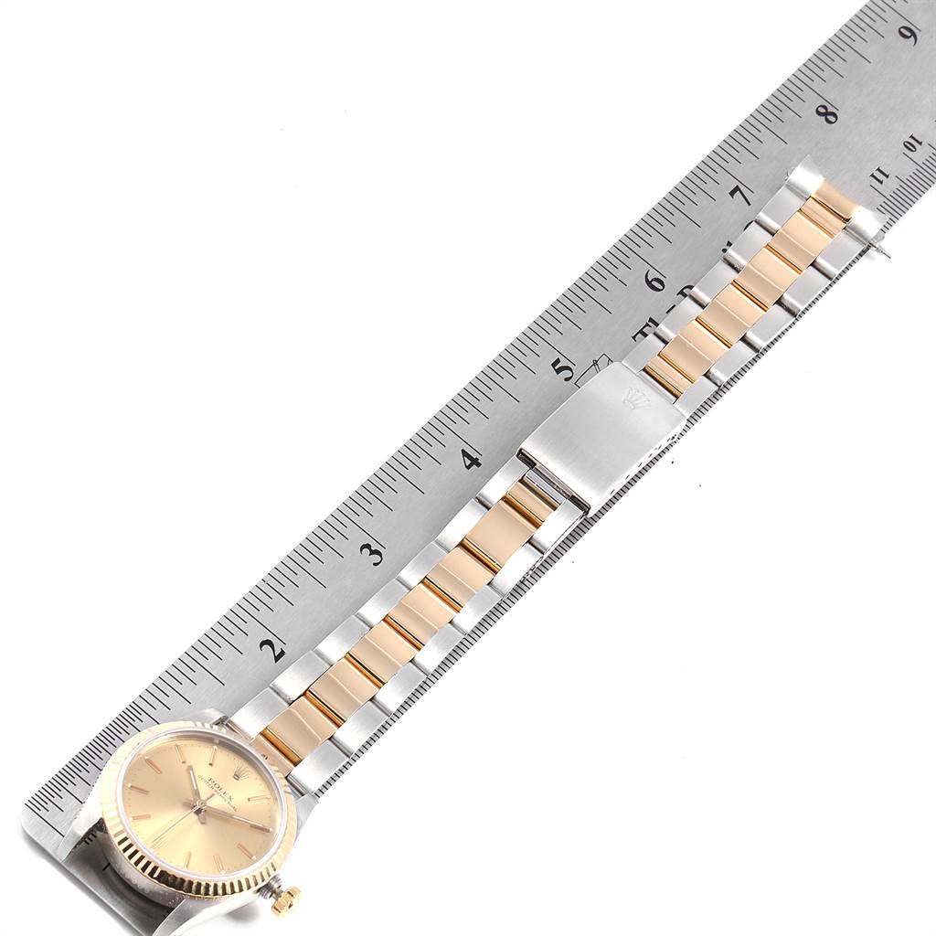 The image shows a Rolex Mid-Size 67513 Women's Steel and Gold (two tone) Champagne Dial 67513 Women's Steel and Gold (two tone) Champagne Dial watch laid flat with a metal ruler, displaying the face, crown, and full bracelet in a top-down angle.