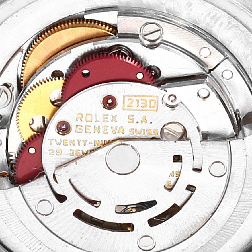 The image shows the intricate internal mechanism of a Rolex Mid-Size 67513 Women's Steel and Gold (two tone) Champagne Dial 67513 Women's Steel and Gold (two tone) Champagne Dial model, highlighting gears and engravings.
