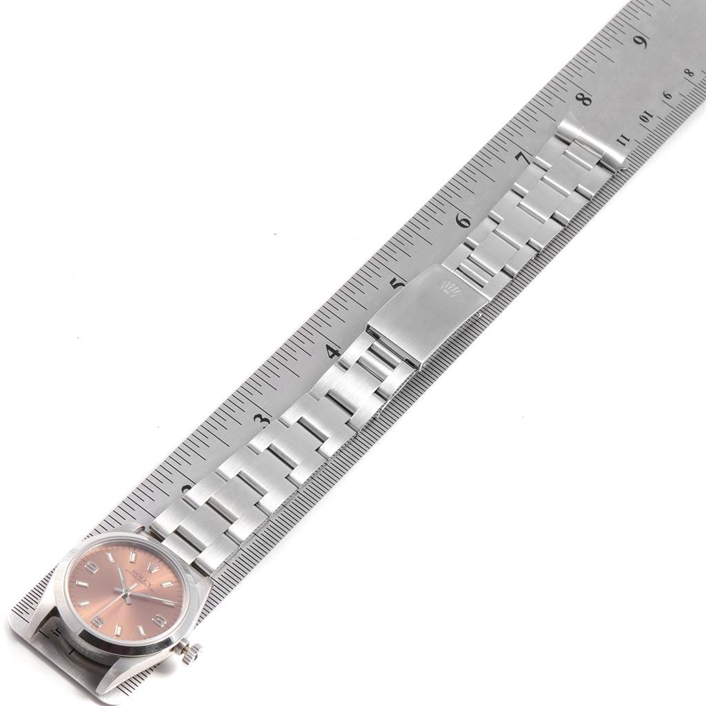 This image shows a Rolex Mid-Size 67480 Women's Stainless Steel Pink Dial 67480 Women's Stainless Steel Pink Dial watch laid flat with its bracelet extended next to a ruler.