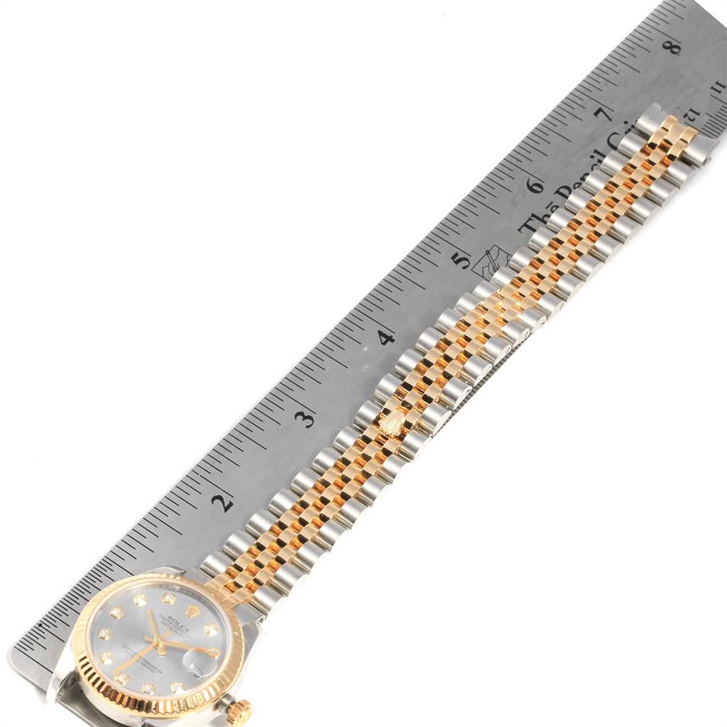 The image shows a Rolex Mid-Size 178273 Women's Steel and Gold (two tone) Silver Dial 178273 Women's Steel and Gold (two tone) Silver Dial model watch laid flat with a metal ruler measuring its length.