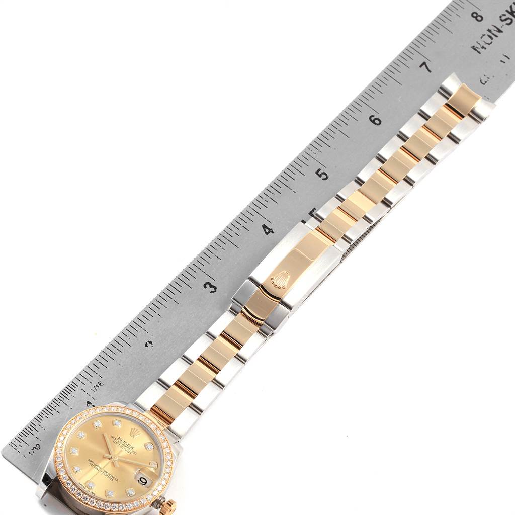 The Rolex Mid-Size 178383 Women's Steel and Gold (two tone) Champagne Dial 178383 Women's Steel and Gold (two tone) Champagne Dial model watch is shown at a top-down angle, displaying its face, band, and clasp alongside a ruler for scale.