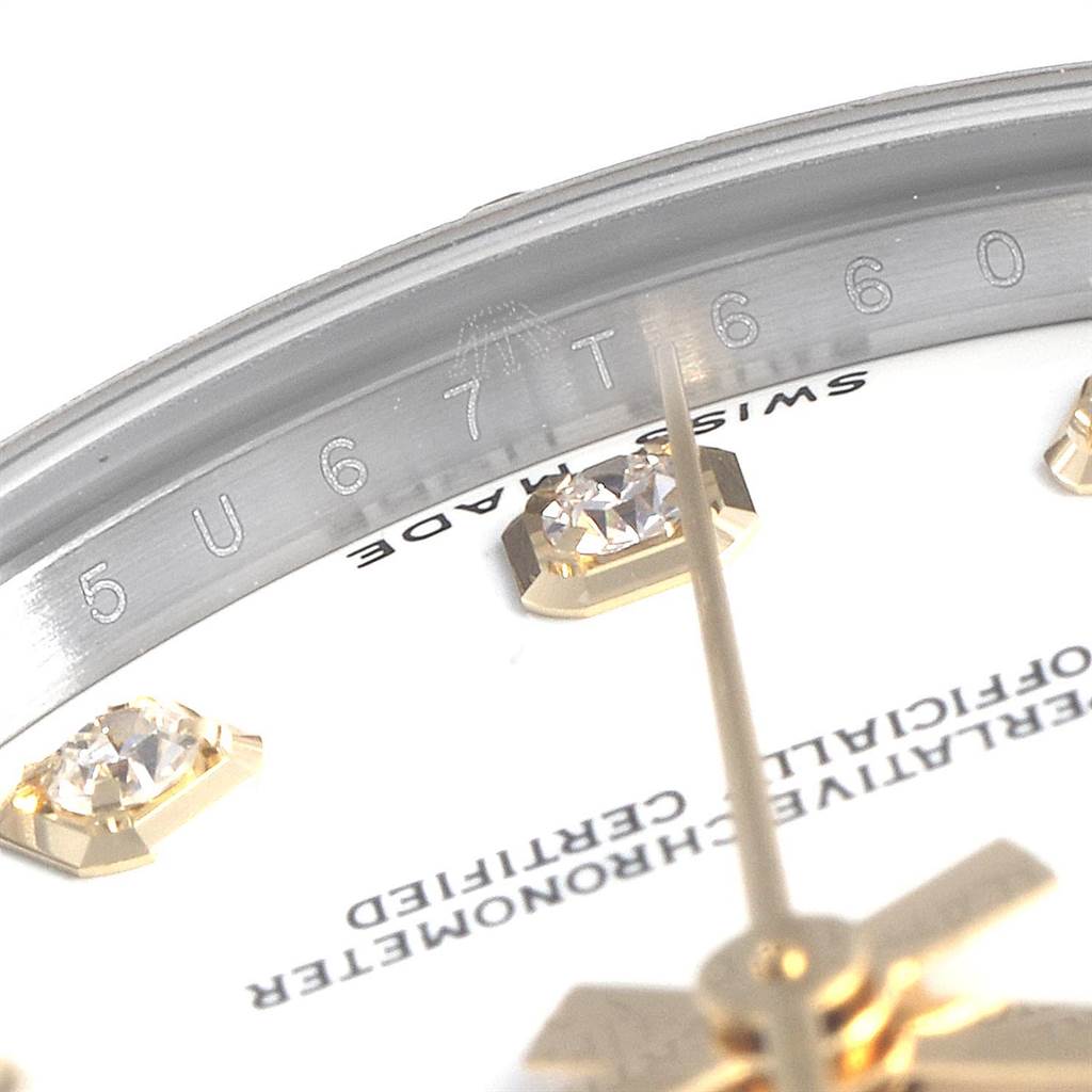 This close-up image of a Rolex Mid-Size 178343 Women's Steel and Gold (two tone) White Dial 178343 Women's Steel and Gold (two tone) White Dial watch features the dial, diamond hour markers, and partial view of the inner bezel with engravings.
