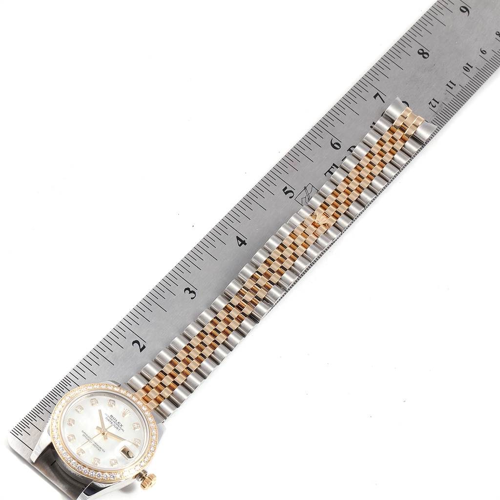This image shows a Rolex Mid-Size 178383 Women's Steel and Gold (two tone) Mother of Pearl Dial 178383 Women's Steel and Gold (two tone) Mother of Pearl Dial watch placed next to a ruler, highlighting the dial and the two-tone bracelet.