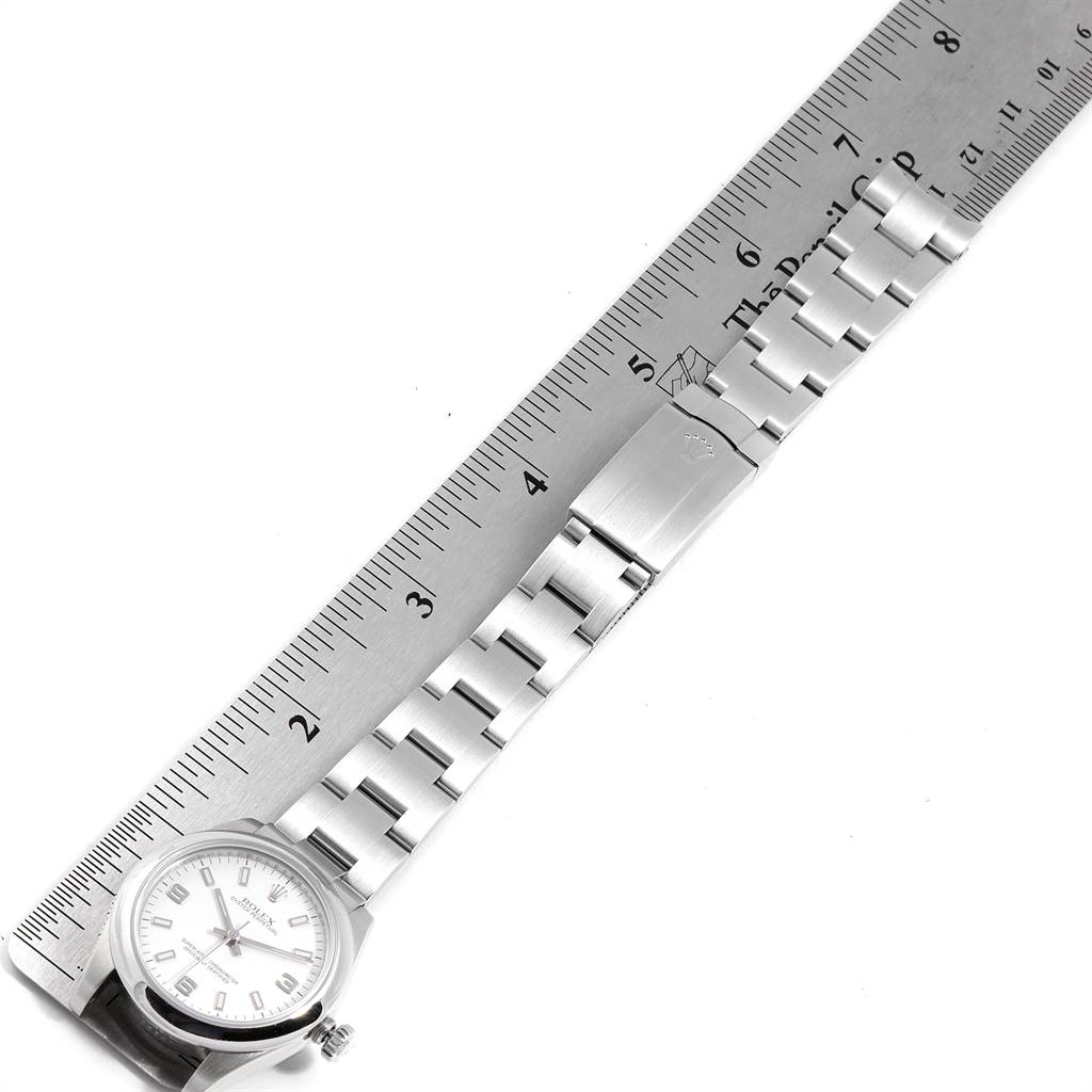The image shows a Mid-Size Rolex watch laid next to a ruler, displaying the watch face and metal band.