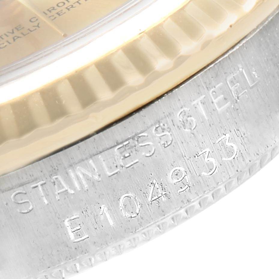 This close-up image shows the bezel and engraved serial number of a Rolex Mid-Size 68273 Women's Steel and Gold (two tone) Champagne Dial 68273 Women's Steel and Gold (two tone) Champagne Dial watch, including text "STAINLESS STEEL" and "E104933".