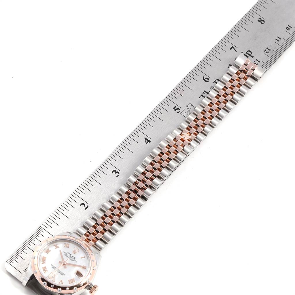 A mid-size Rolex watch is shown from the top, displaying its dial, bezel, and full bracelet aligned with a ruler.