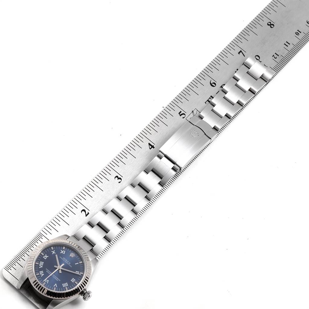 The image shows a top-down view of a Mid-Size Rolex watch with a metal bracelet, a blue dial, and a ruler for size reference.