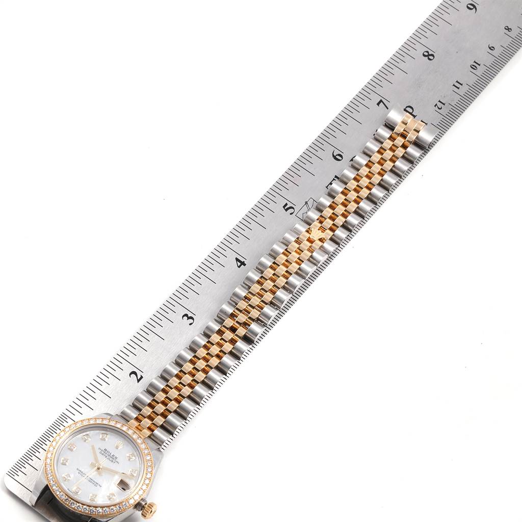 The Rolex Mid-Size 178383 Women's Steel and Gold (two tone) Mother of Pearl Dial 178383 Women's Steel and Gold (two tone) Mother of Pearl Dial watch is shown from a top-down angle with a ruler, highlighting its face and bracelet.