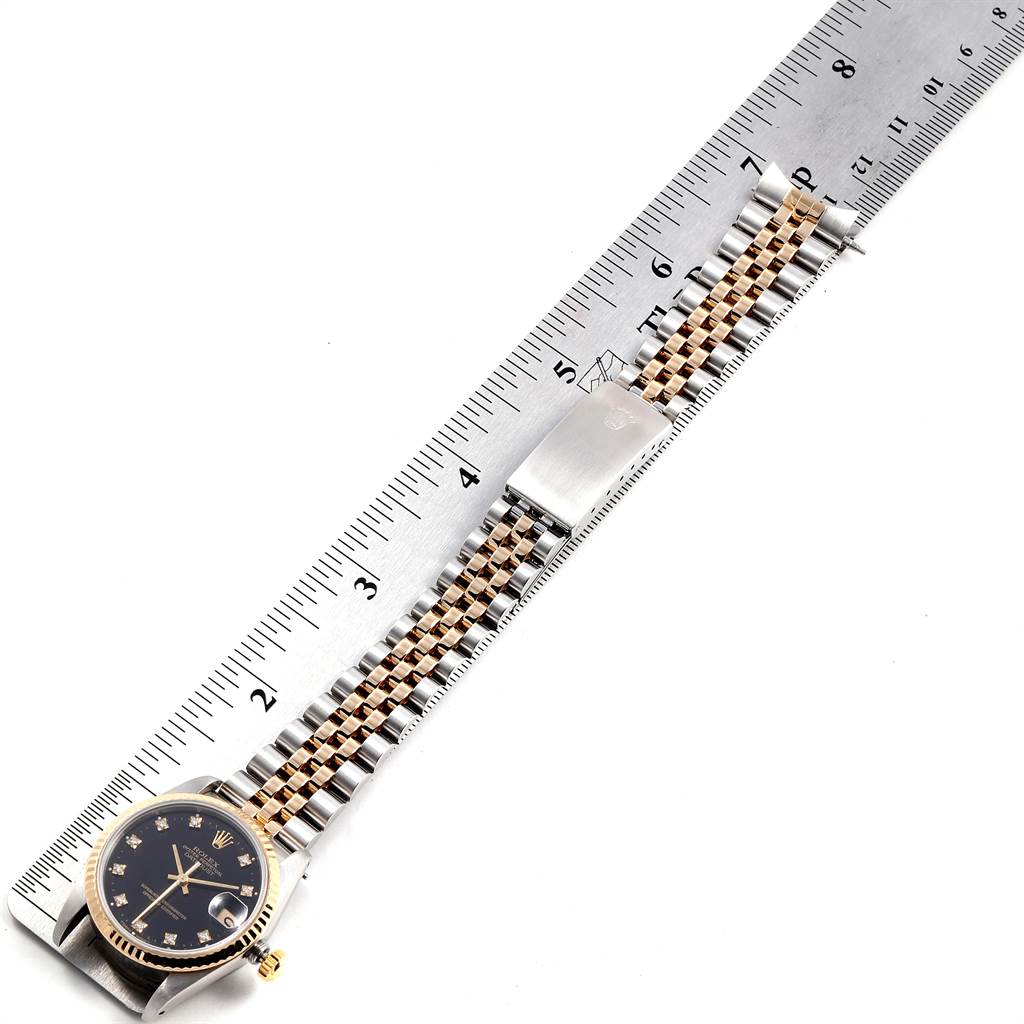 The image shows a Rolex Mid-Size 68273 Women's Steel and Gold (two tone) Black Dial 68273 Women's Steel and Gold (two tone) Black Dial watch laid flat next to a ruler, displaying its face and entire bracelet.