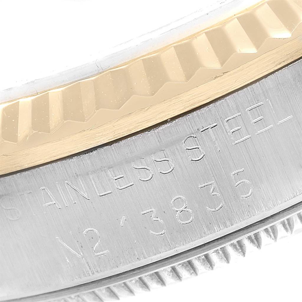 The image shows the side of a mid-size Rolex watch case, highlighting the stainless steel part with engraved text and a gold fluted bezel.