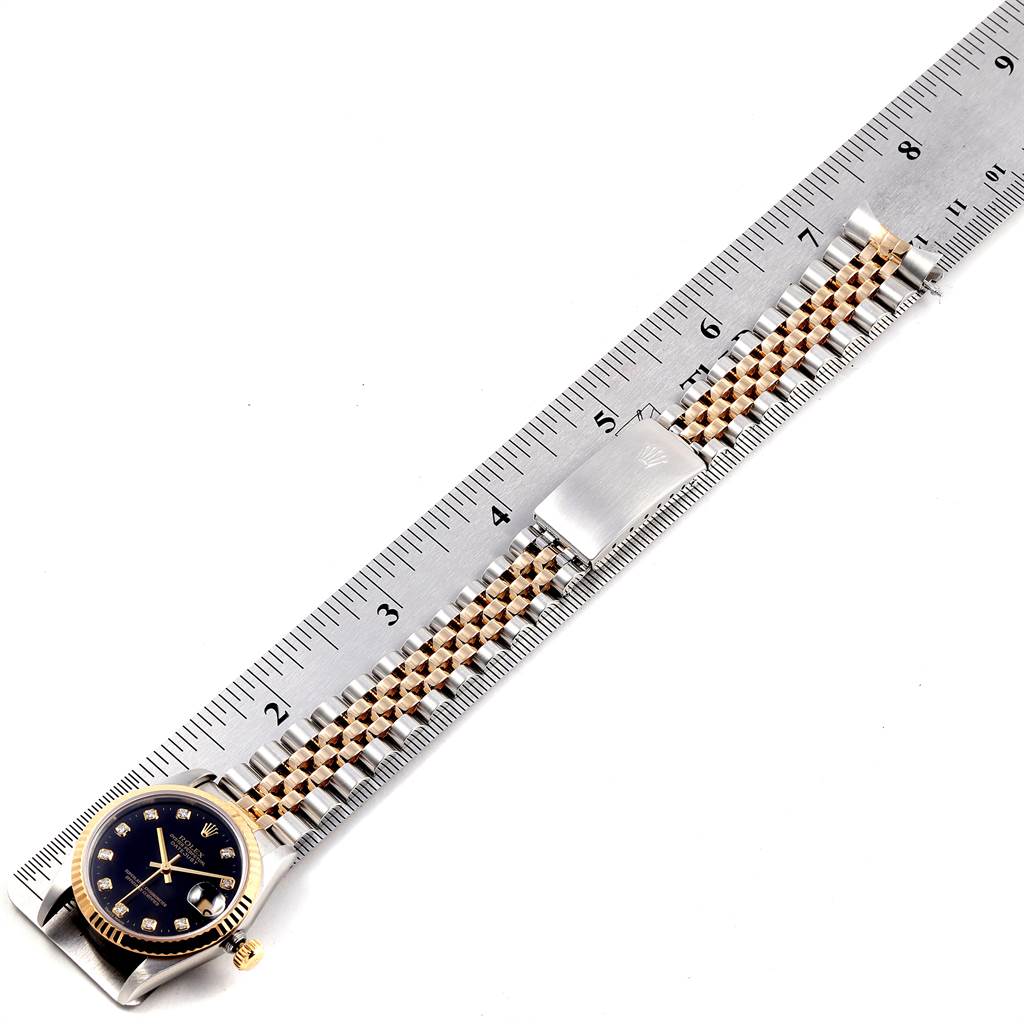 The image shows a Mid-Size Rolex watch laid along a ruler, highlighting the bracelet and dial.