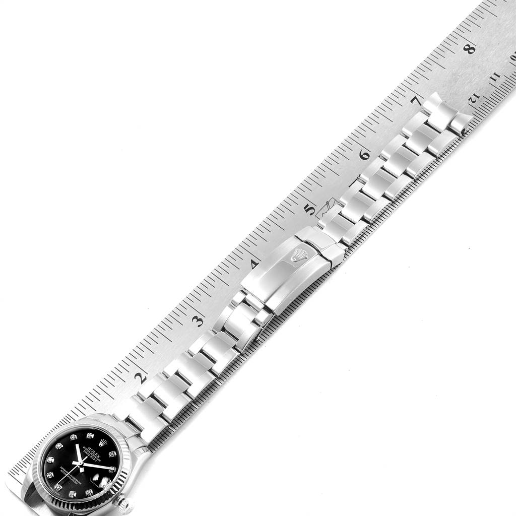This image shows the full bracelet and face of a Rolex Mid-Size 178274 Women
s Stainless Steel Black Dial 178274 Women
s Stainless Steel Black Dial model watch placed next to a ruler for scale.
