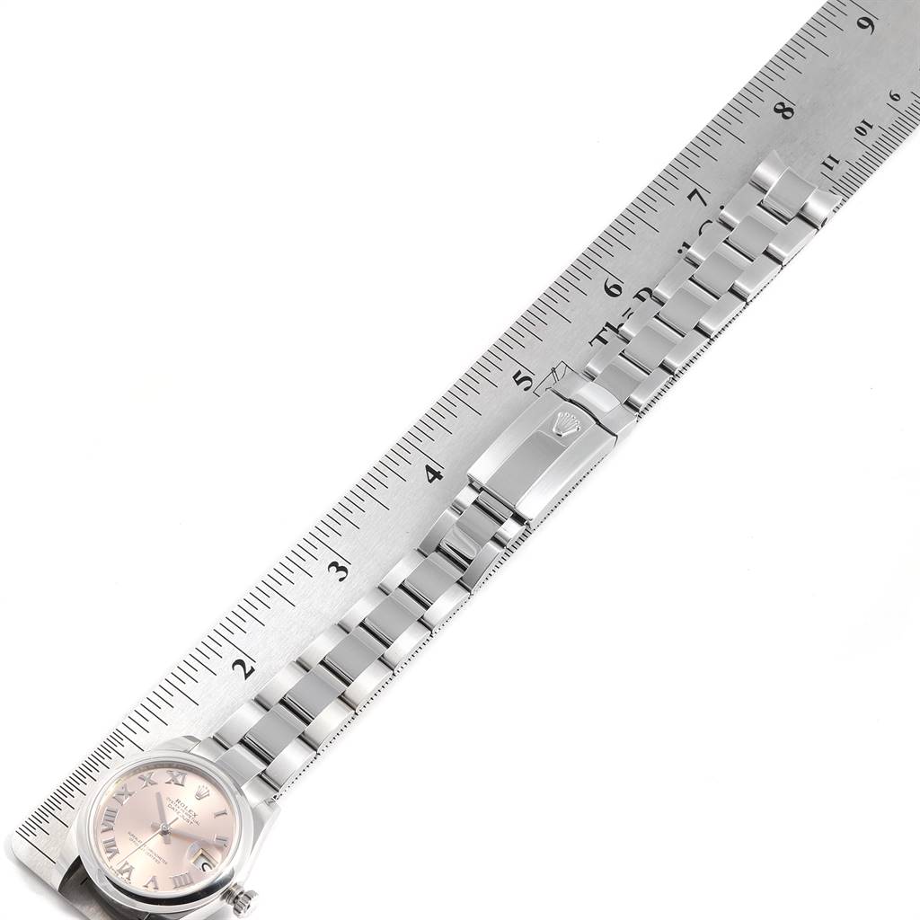 The image shows a flat, overhead view of a Mid-Size Rolex watch with its band next to a ruler.