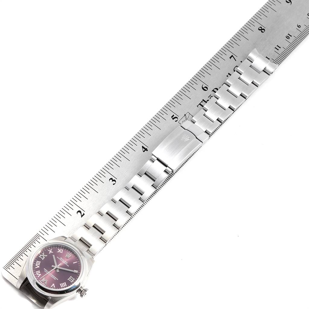 The image shows a Rolex Mid-Size 177200 Women's Stainless Steel Burgundy Dial 177200 Women's Stainless Steel Burgundy Dial watch laid flat with its bracelet fully extended alongside a ruler.