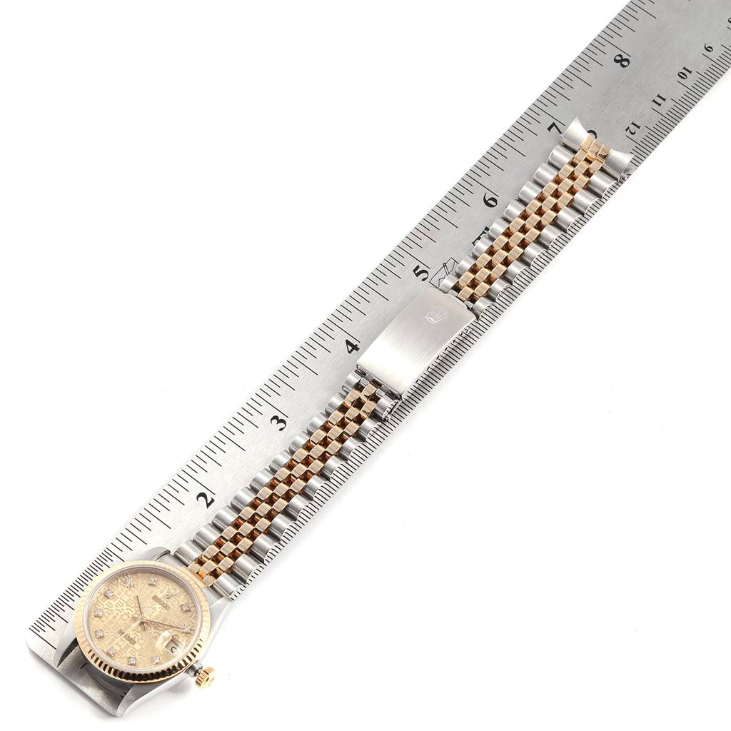 The Rolex Mid-Size 68273 Women's Steel and Gold (two tone) Champagne Dial 68273 Women's Steel and Gold (two tone) Champagne Dial watch is shown from a top-down angle, highlighting its face, bracelet, ruler for scale, and clasp.