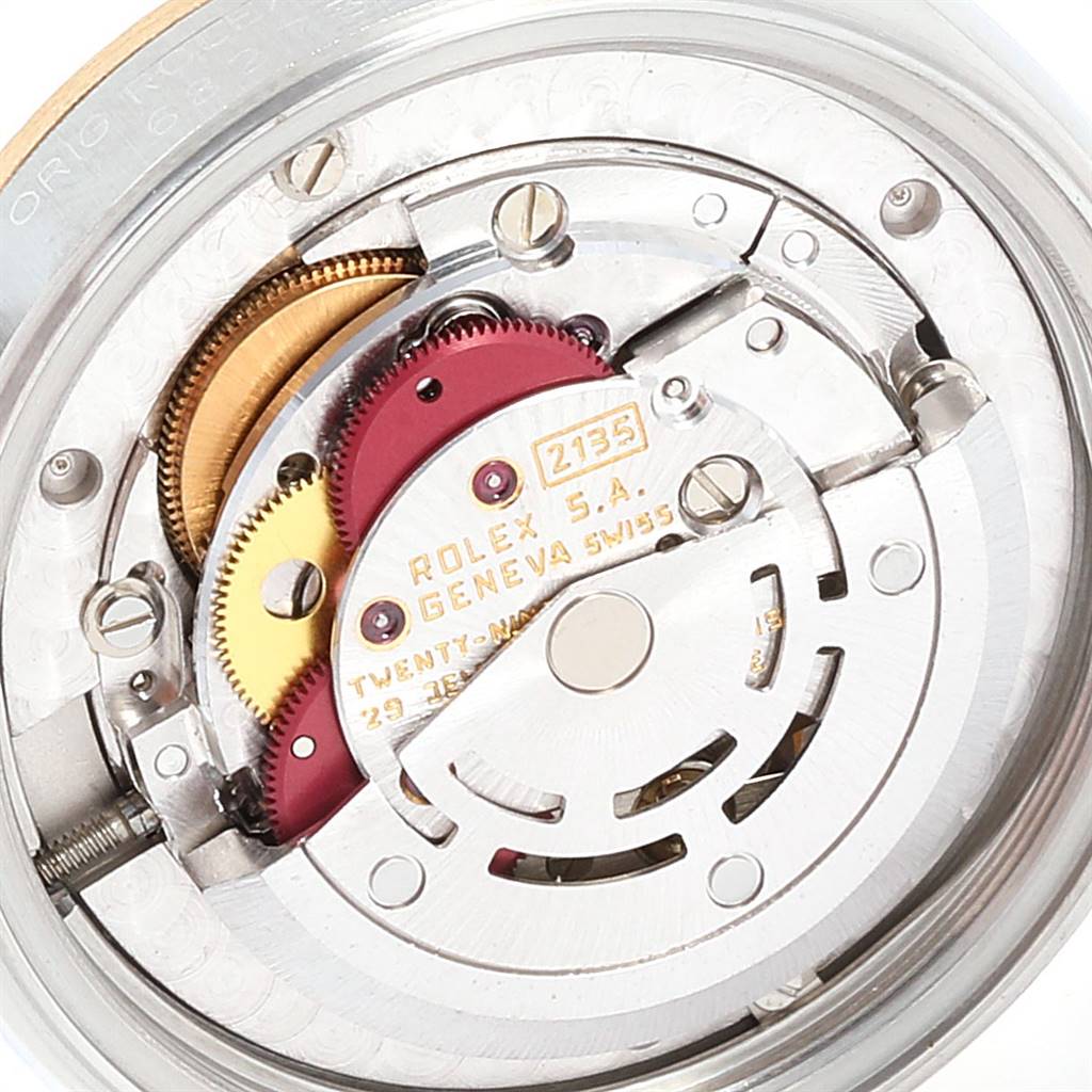 The image shows a detailed view of the movement mechanism inside a mid-size Rolex watch model, focusing on its gears and rotor.