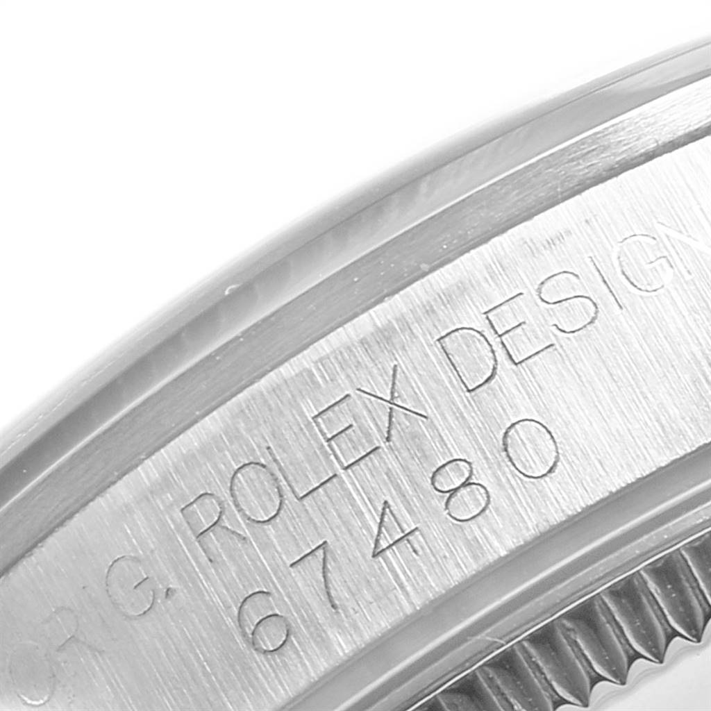 This image shows a close-up of the case side of a Rolex Mid-Size 67480 Women's Stainless Steel Blue Dial 67480 Women's Stainless Steel Blue Dial model, highlighting the engraved serial number and "Rolex Design" text.