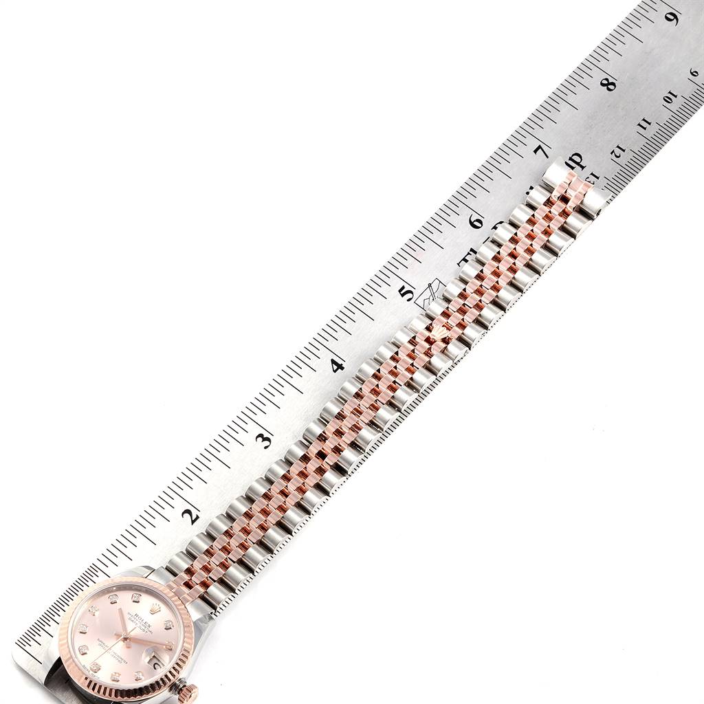 This image shows a Rolex Mid-Size 178271 Women's Steel and Gold (two tone) Pink Dial 178271 Women's Steel and Gold (two tone) Pink Dial watch laid flat next to a ruler, displaying its face and bracelet.