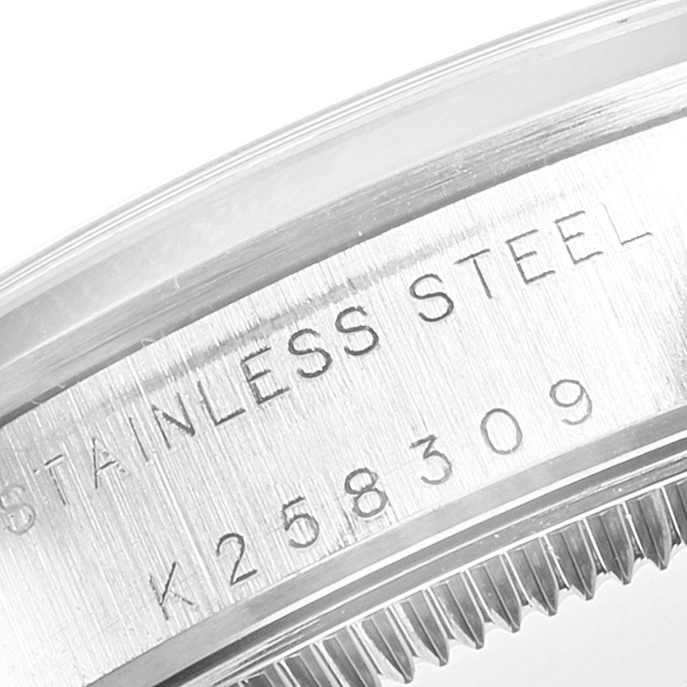 This close-up of a Rolex Mid-Size 77080 Women
s Stainless Steel Black Dial 77080 Women
s Stainless Steel Black Dial model watch shows the stainless steel case with engraved text and serial number.