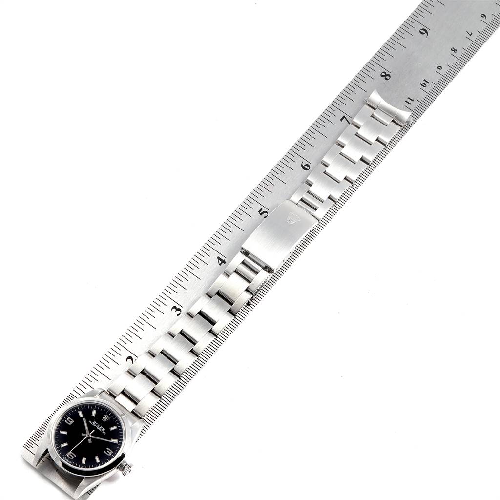 The image shows a Mid-Size Rolex watch laid flat next to a ruler, highlighting the face and metal band.