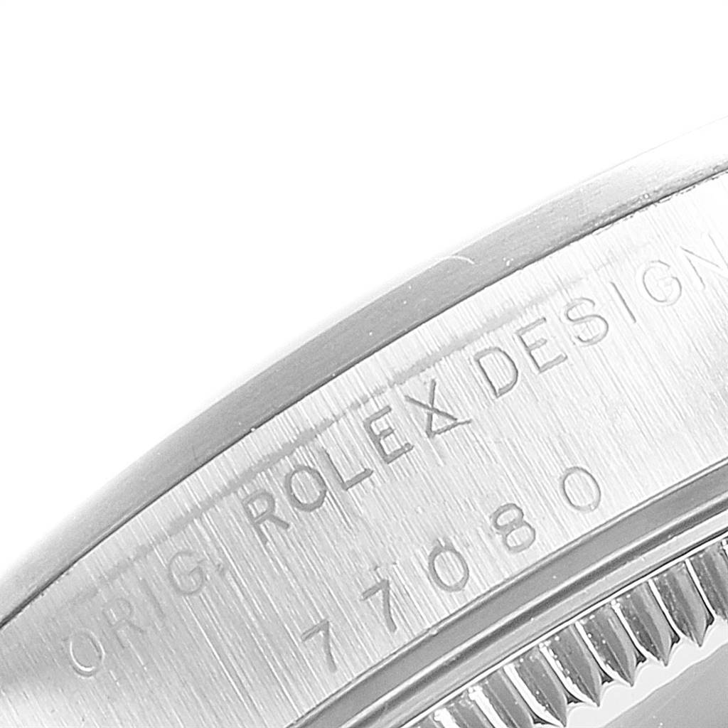 The image shows a close-up of a Rolex Mid-Size 77080 Women's Stainless Steel Black Dial 77080 Women's Stainless Steel Black Dial model, revealing part of the case with engraved text.