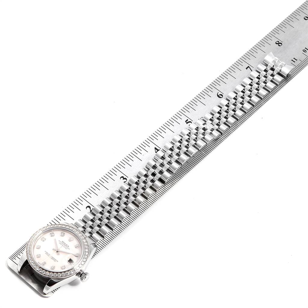 The image shows a Rolex Mid-Size 178384 Women
s Stainless Steel Mother of Pearl Dial 178384 Women
s Stainless Steel Mother of Pearl Dial watch
s face and bracelet next to a ruler for measurement.