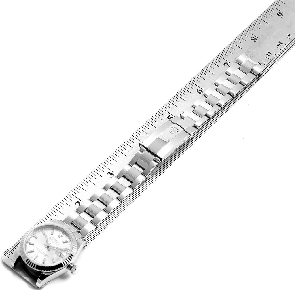 This image shows a side view of a Rolex Mid-Size 178274 Women's Stainless Steel Silver Dial 178274 Women's Stainless Steel Silver Dial model, displaying the face and entire bracelet next to a ruler.