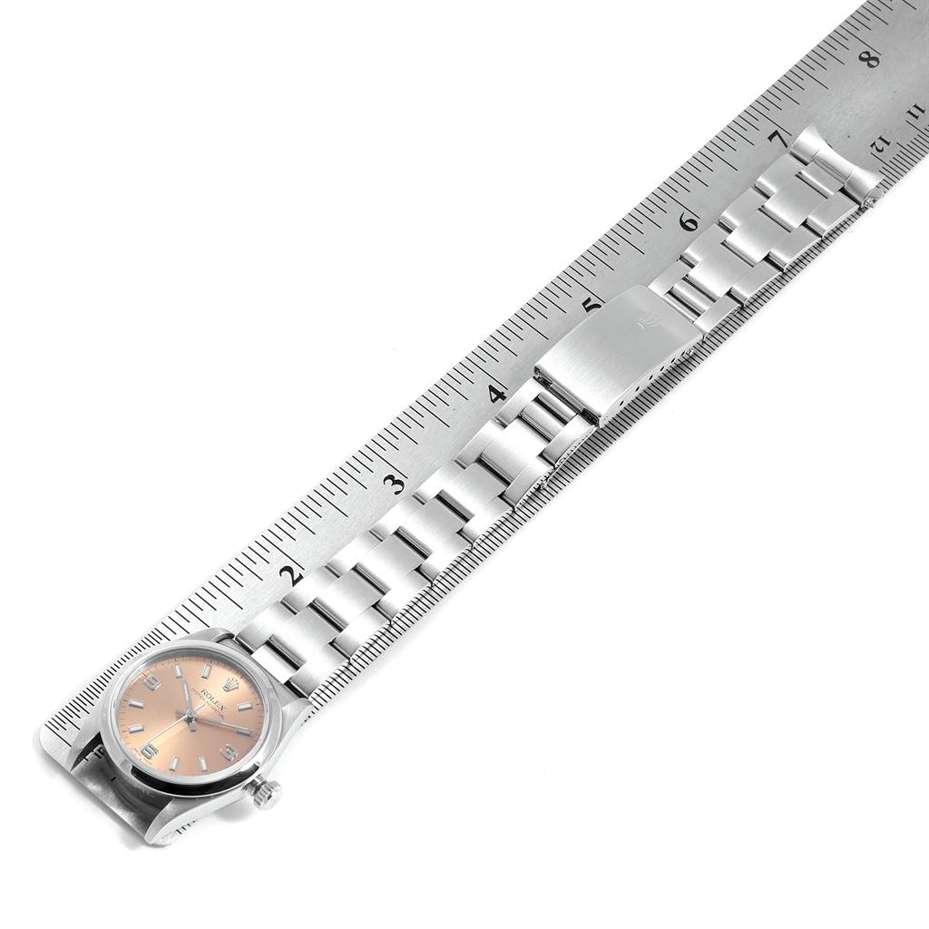 The image shows a top-down view of a Rolex Mid-Size 77080 Women's Stainless Steel Pink Dial 77080 Women's Stainless Steel Pink Dial watch, highlighting its bracelet and clasp along a ruler for scale.