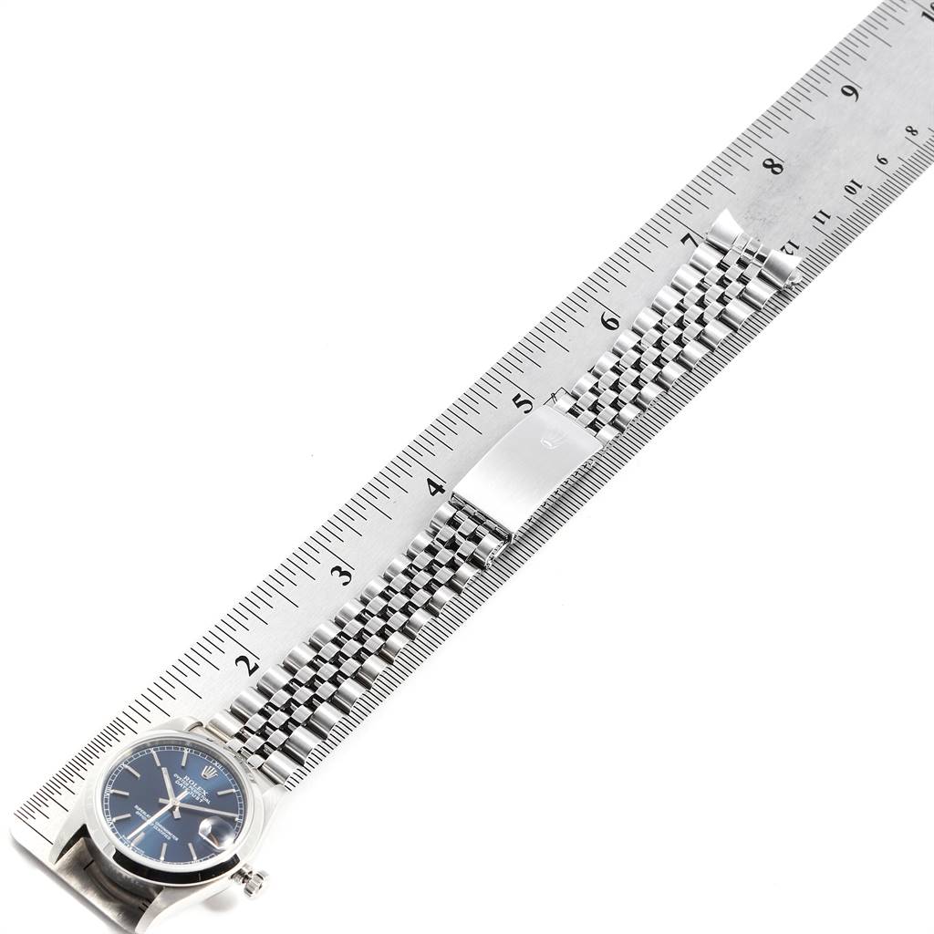 The Rolex Mid-Size 78240 Women
s Stainless Steel Blue Dial 78240 Women
s Stainless Steel Blue Dial watch is shown lying flat, with its face and bracelet aligned alongside a ruler for measurement.