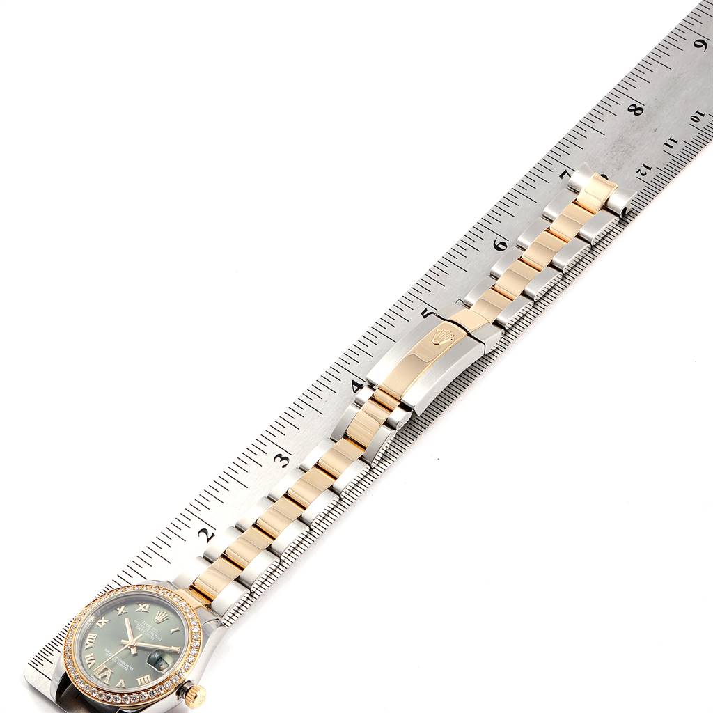 The Mid-Size Rolex watch is shown from an overhead angle, with the entire watch and bracelet laid next to a ruler.